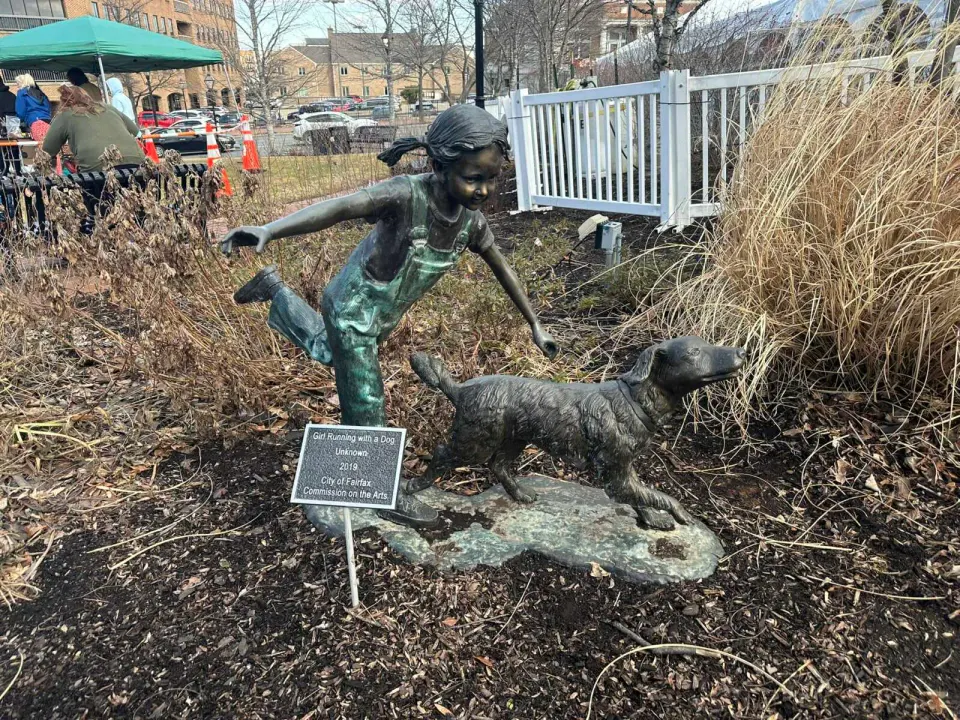 A statue of a Girl Running with a Dog in Fairfax City (staff photo by Angela Woolsey)